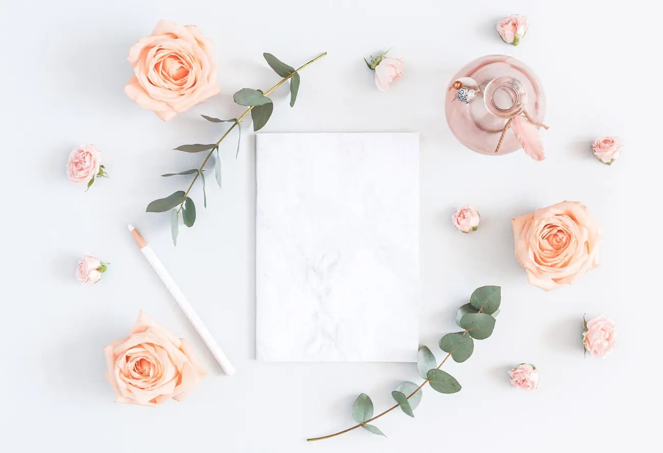 Helle Karte mit Rosen, Eukalyptus und Stift auf weißem Hintergrund