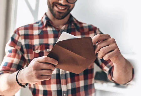 Mann öffnet einen Umschlag als persönliche Inspiration für Hochzeitseinladungen zum Selbstgestalten